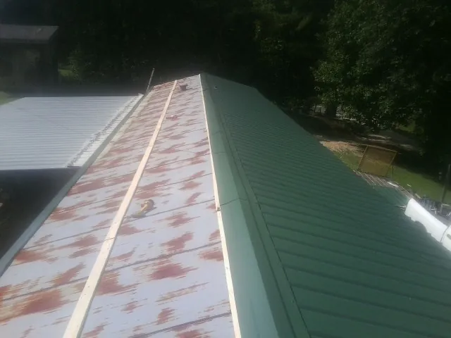 Old rusted panels beside newly installed green metal roofing — Wind Damage Roof Repair by Roofing Brothers in Aroda