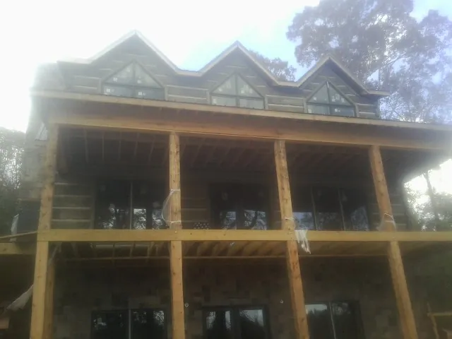 Dormers and porch framing on a large log home under construction — Roof Coating work by our crew in Aroda