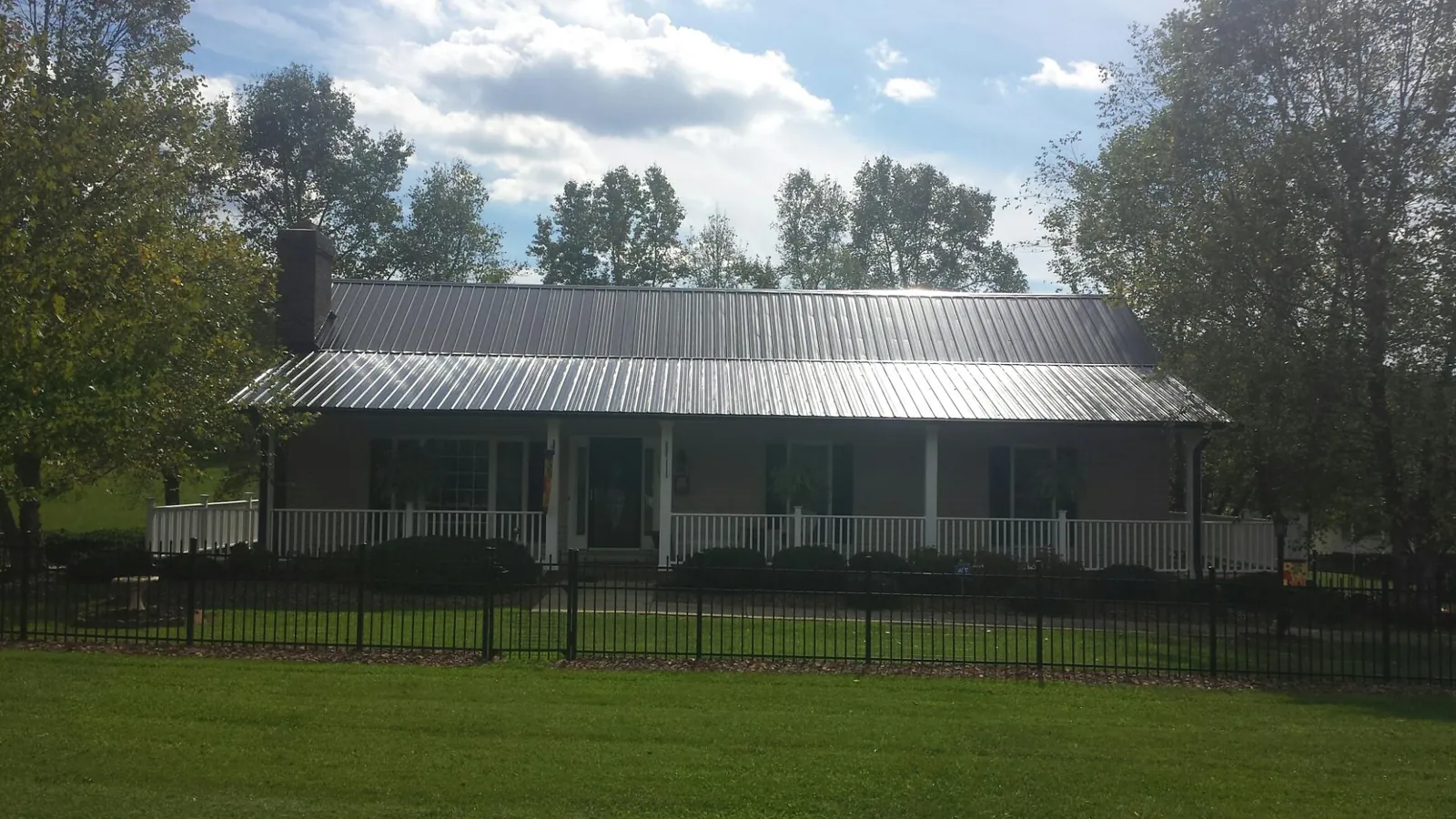 Gray metal roof on a brick ranch with a full width front porch — Gutter Guard Installation work by our crew in Aroda