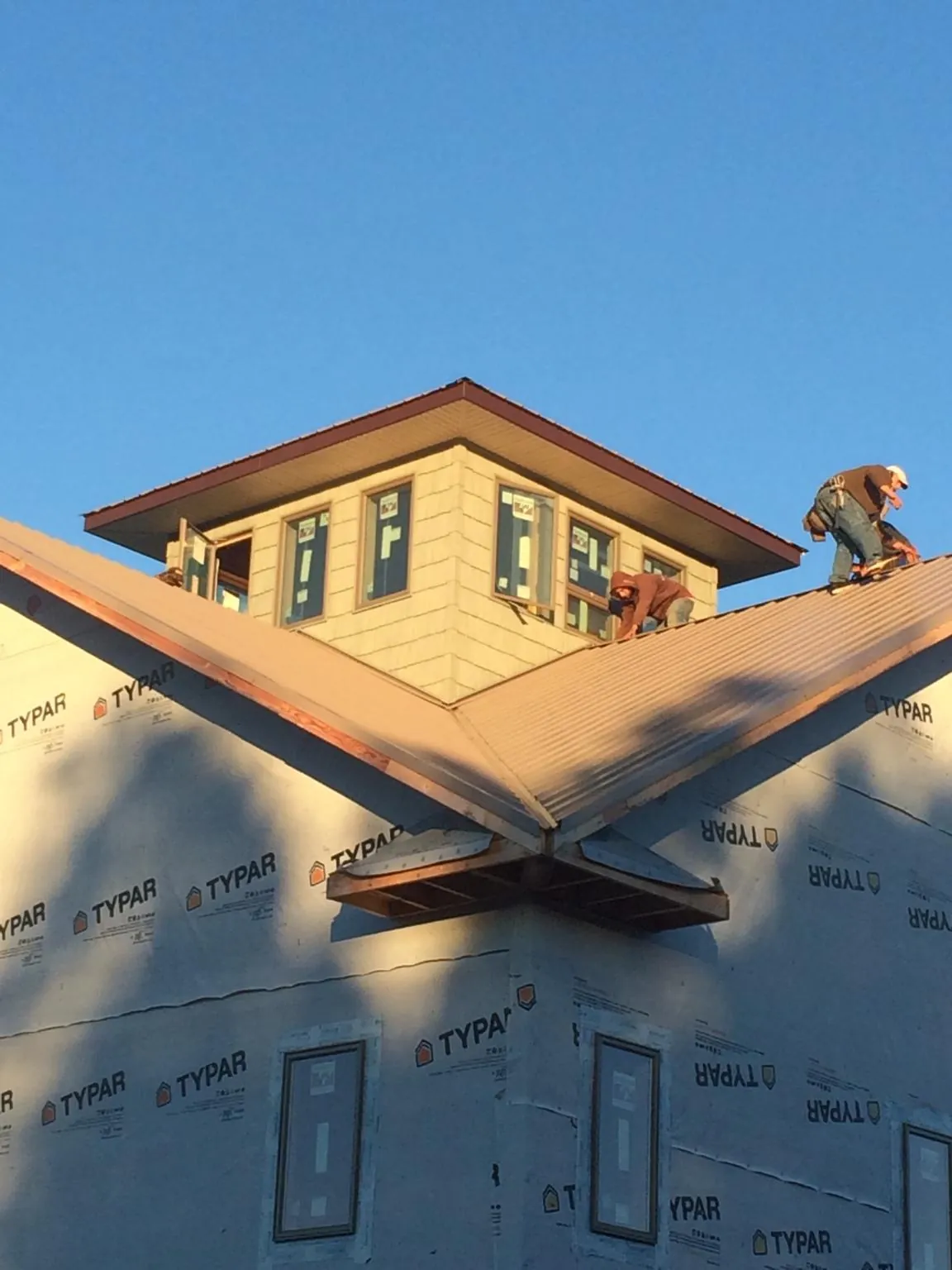 Roofers working around a rooftop cupola on a new metal roof at sunset — Roof Waterproofing in Aroda by Roofing Brothers
